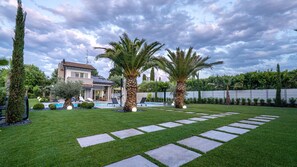 A residential property with a swimming pool, palm trees, and a well-maintained lawn.