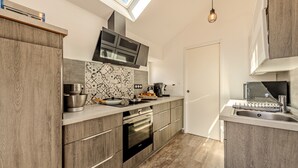 Eine moderne Küche mit Oberlicht, eingebautem Backofen und großem Fenster.