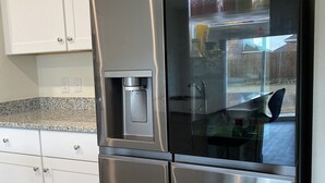Un refrigerador de acero inoxidable con dispensador de agua, compartimento congelador y puerta de vidrio.
