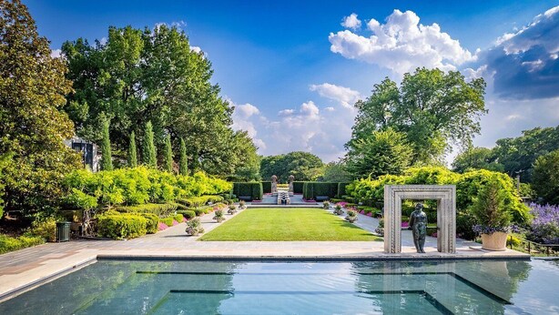 Una piscina con vistas despejadas del jardín circundante y una estatua.