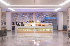 A modern hotel lobby with a marble wall, a reception desk, and a coffee station. - Wyndham Jomtien Pattaya (Sattahip)