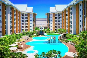 A modern hotel with a central swimming pool, multiple balconies, and lush greenery. - Wyndham Jomtien Pattaya (Sattahip)