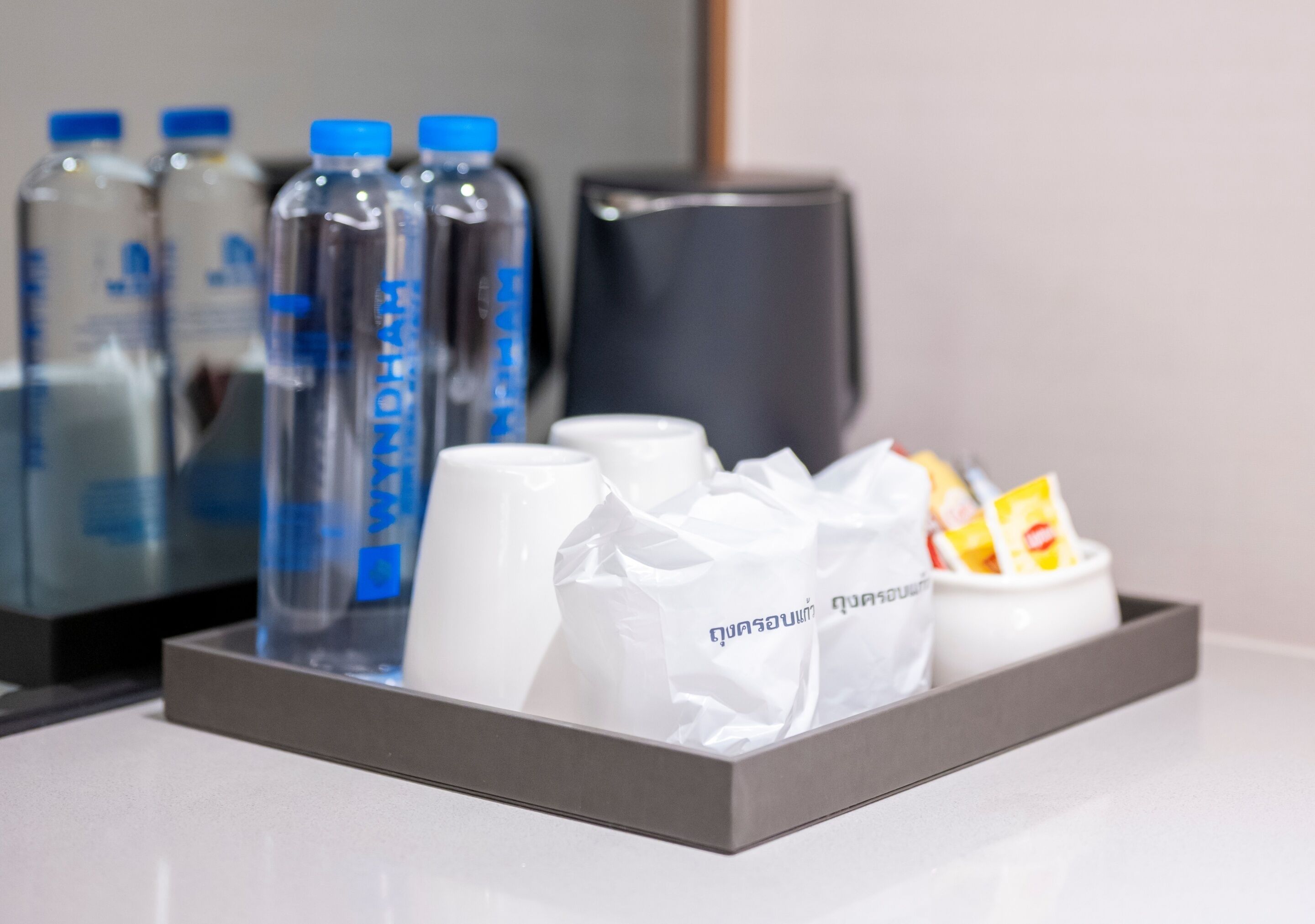 A tray with bottled water, a white mug, and a white container with snacks.