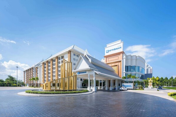 A hotel with a modern design, featuring a prominent entrance with a covered walkway and a large building with a distinctive roof. - Wyndham Jomtien Pattaya (Sattahip)