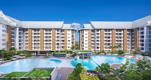 A modern hotel with multiple balconies, a central pool, and lush landscaping. - Wyndham Jomtien Pattaya (Sattahip)