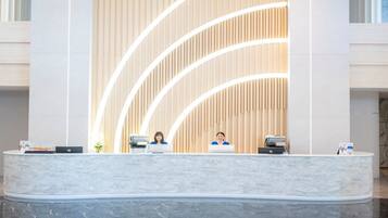 A reception desk with two staff members, a modern design with vertical wooden slats and a marble counter.