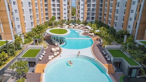 Un hotel con múltiples piscinas, zonas de estar al aire libre y un jardín en la azotea.