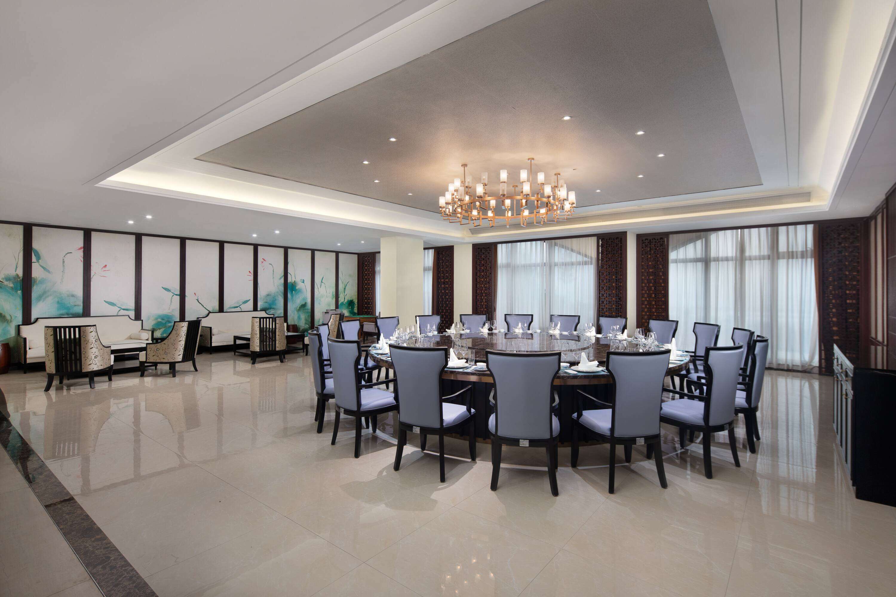 A spacious dining area with a large round table set for a meal, surrounded by chairs.