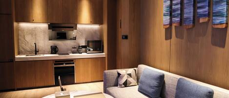A modern kitchen with wooden cabinets and a marble countertop, a built-in oven, and a coffee machine.