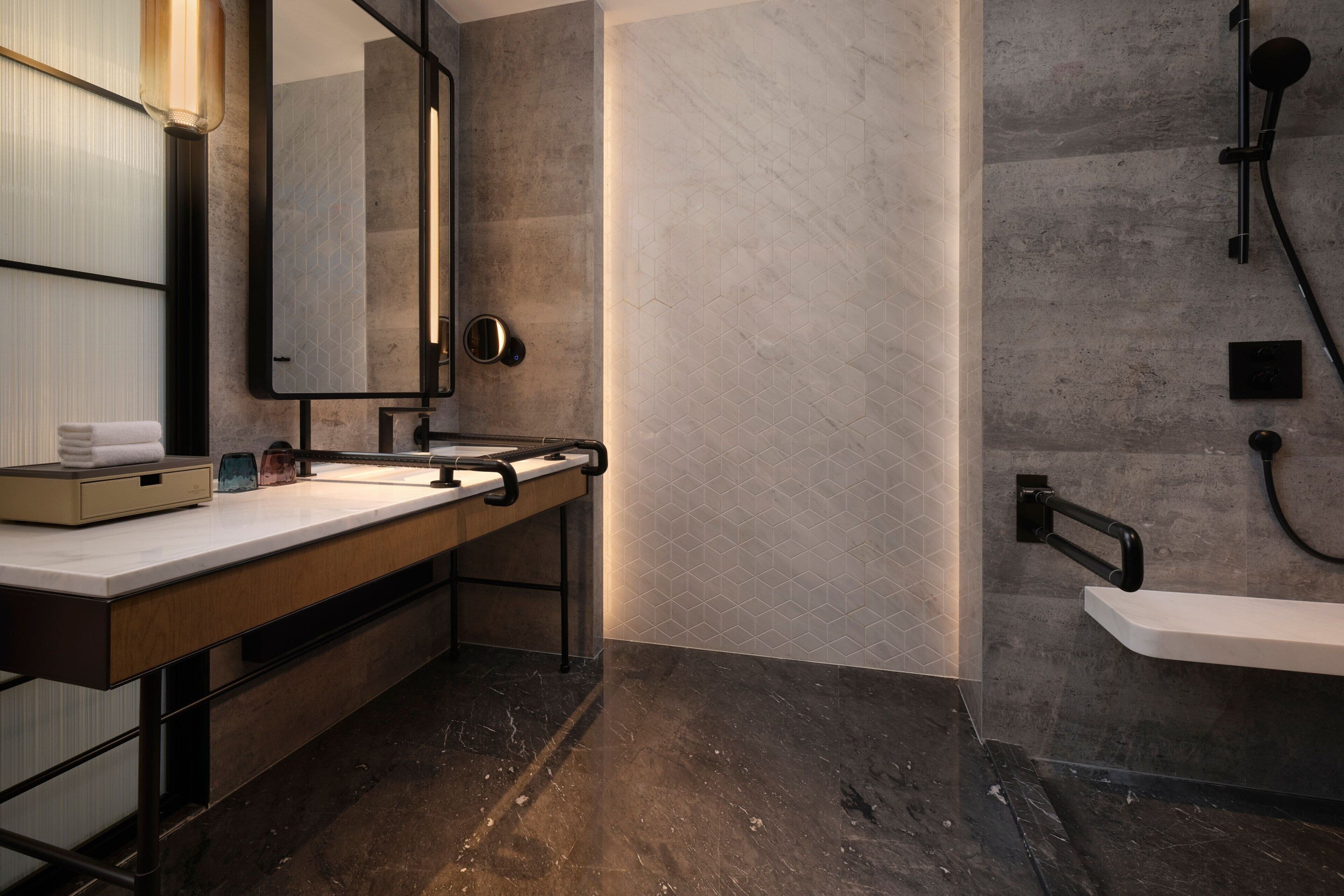 A modern bathroom with a marble sink, a large mirror, and a shower area.