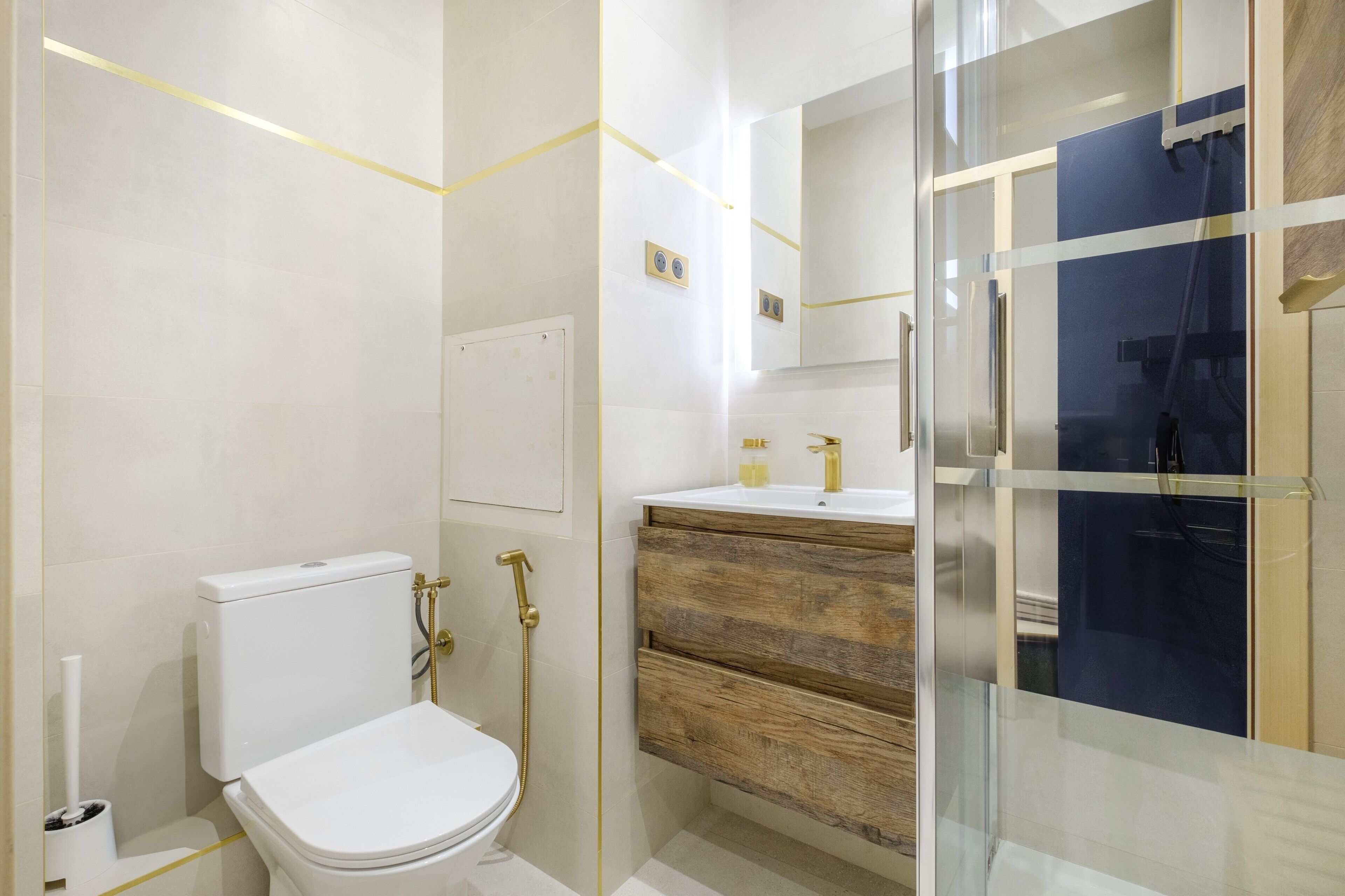 A modern bathroom with a toilet, a wooden vanity, and a glass shower enclosure.