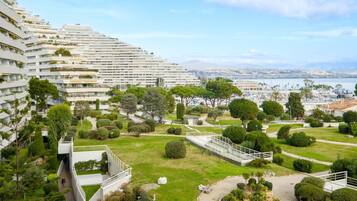 Un hôtel moderne doté d’un jardin aménagé, d’une marina en arrière-plan et offrant une vue sur la ville.
