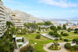 Een modern hotel met een aangelegde tuin, een jachthaven op de achtergrond en uitzicht op de stad.