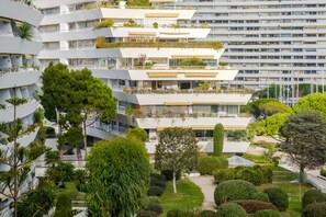 Un immeuble moderne à plusieurs étages, doté de balcons, de verdure et d’un jardin bien entretenu.