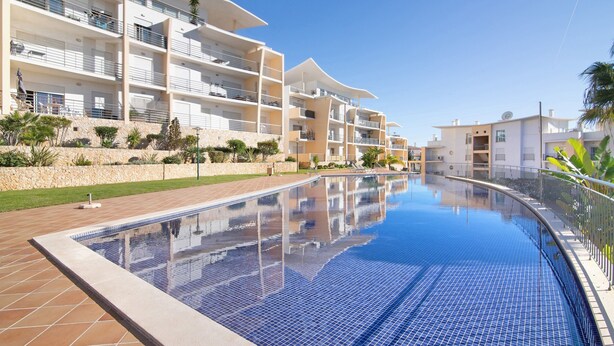Un hotel moderno con piscina, balcones y una pared de piedra.