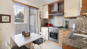 Una cocina compacta con una mesa de comedor, sillas, estufa, horno y lavamanos.