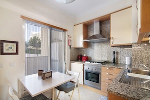 A compact kitchen with a dining table, chairs, a stove, oven, and a sink.