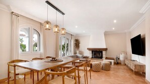 A dining area with a wooden table and chairs, a fireplace, and a television mounted on the wall. - La Casita del Mar – House with Jacuzzi, Garden & Terraces 300 m from the Beach in Torremolinos (Torremolinos)