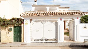 A white building with a green gate, a tiled roof, and a sign indicating a public space. - La Casita del Mar – House with Jacuzzi, Garden & Terraces 300 m from the Beach in Torremolinos (Torremolinos)