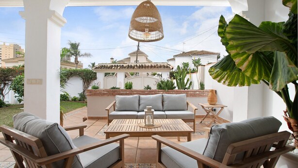 An outdoor patio with a wooden table, two chairs, a sofa, and a hanging light fixture. - La Casita del Mar – House with Jacuzzi, Garden & Terraces 300 m from the Beach in Torremolinos (Torremolinos)