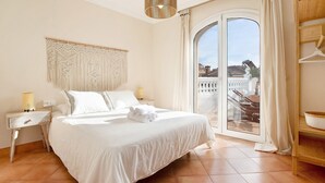 A bedroom with a bed, a macrame wall hanging, a bedside lamp, and a view through a glass door. - La Casita del Mar – House with Jacuzzi, Garden & Terraces 300 m from the Beach in Torremolinos (Torremolinos)