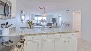 Una cucina moderna con mobili bianchi, un piano di lavoro in granito e un piano cottura integrato.