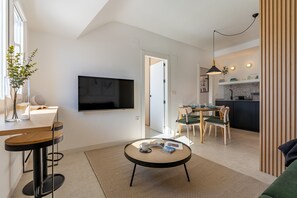 Una sala de estar moderna con televisor, comedor y cocina.