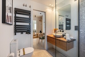 A modern bathroom with a toilet, sink, mirror, and towel rack.
