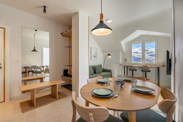 A modern dining area with a round table, benches, and pendant lighting.