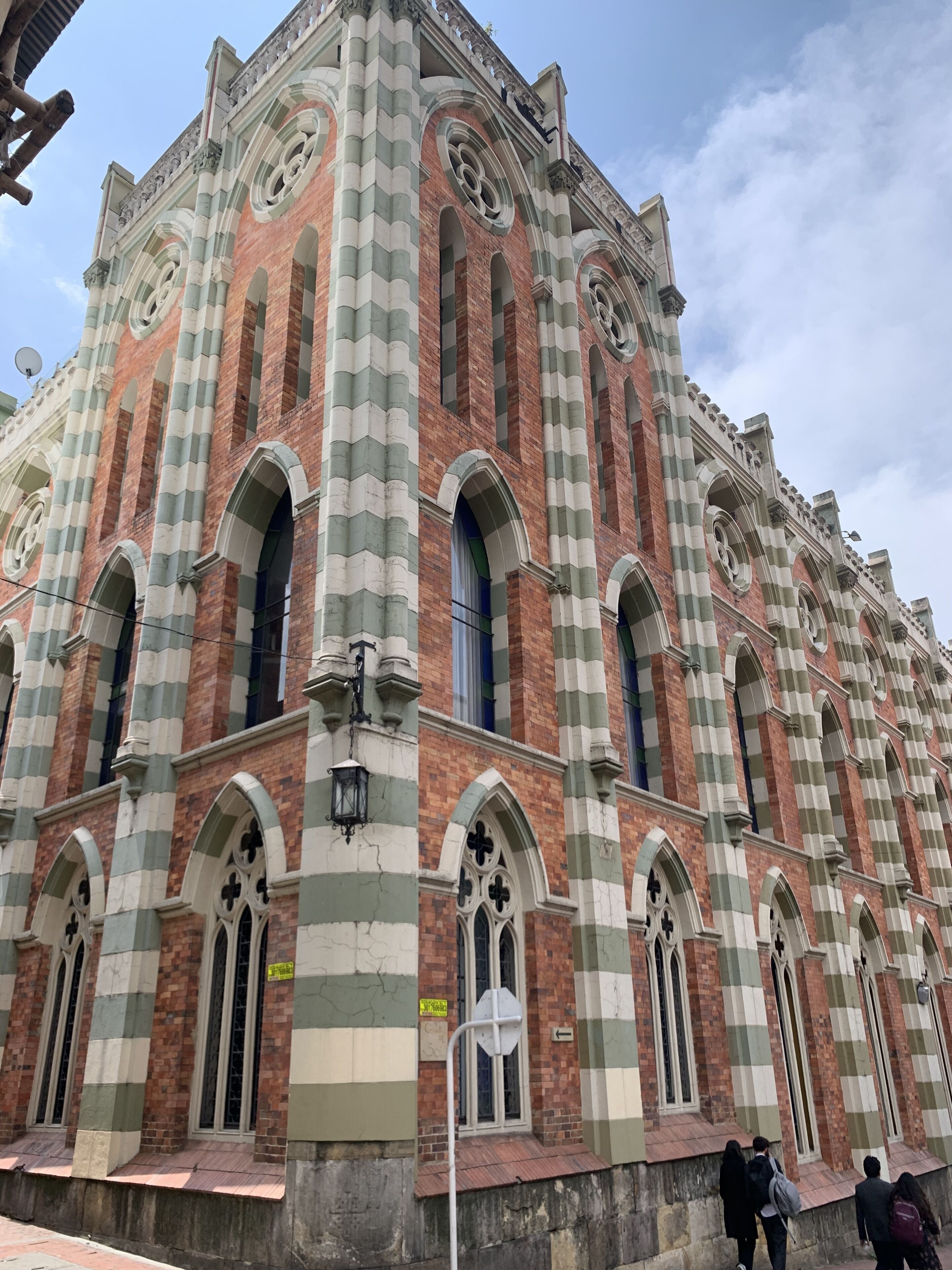 Ein großes, historisches Gebäude mit Schachbrettmuster-Fassade, Bogenfenstern und einem markanten Glockenturm.