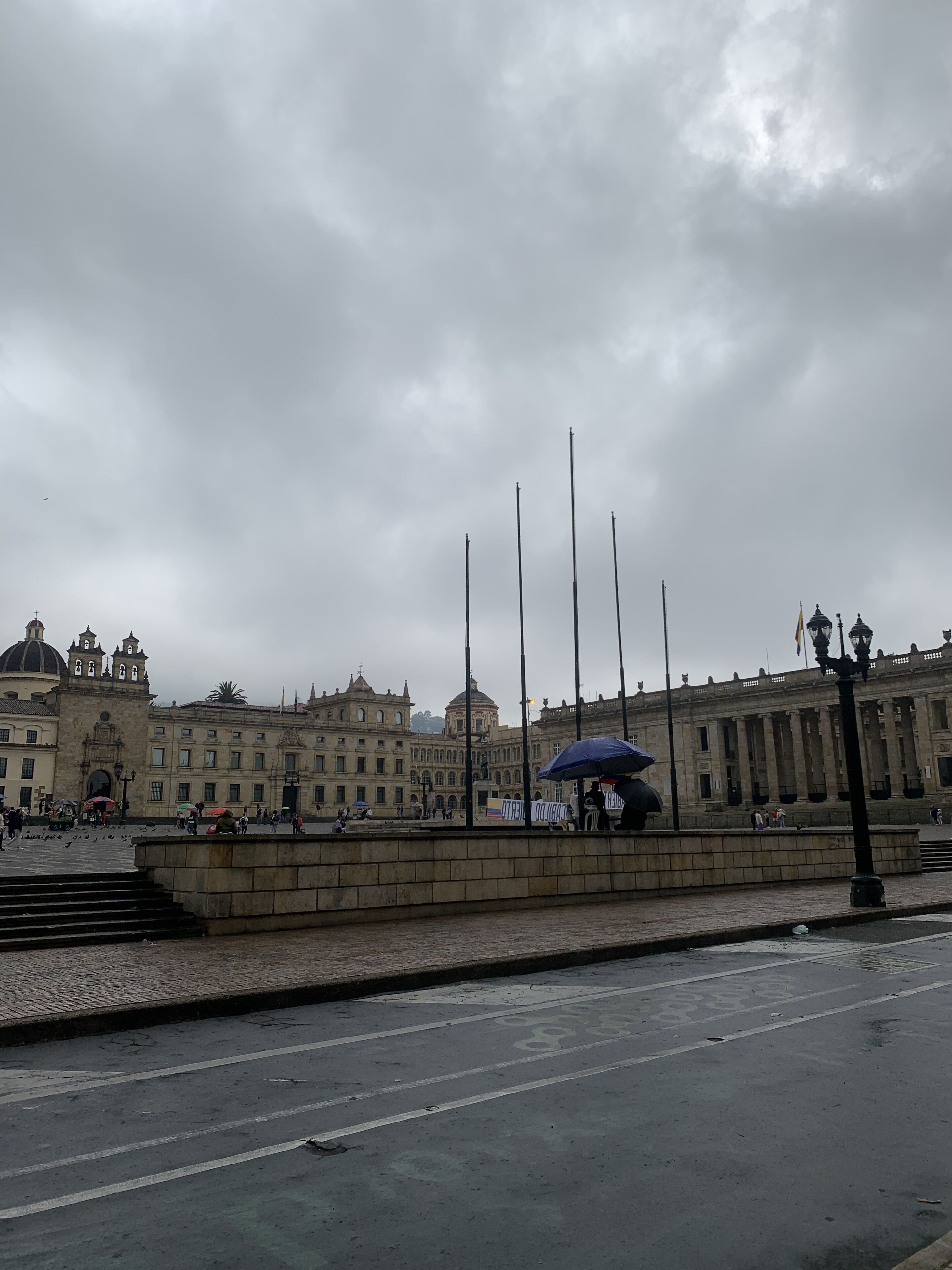 Una plaza histórica con una fuente, un edificio imponente de arquitectura clásica y una estatua.
