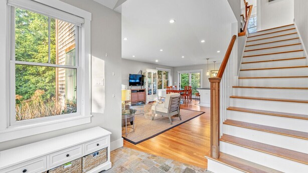 A spacious living area with a staircase, a dining area, and a kitchen visible in the background. - Modern Family Home Walkable to Town (Tisbury)