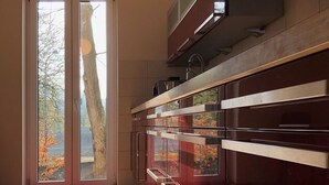 A modern kitchen with a sliding glass door leading to a balcony, a built-in oven, and a view of trees outside. - Schleusenhaus in Hameln (Hameln)