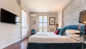 Un dormitorio con cama, televisor, ventana y pared decorada.