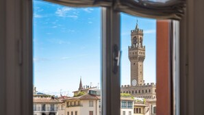 Vista a través de una ventana de un edificio histórico con una torre del reloj destacada.