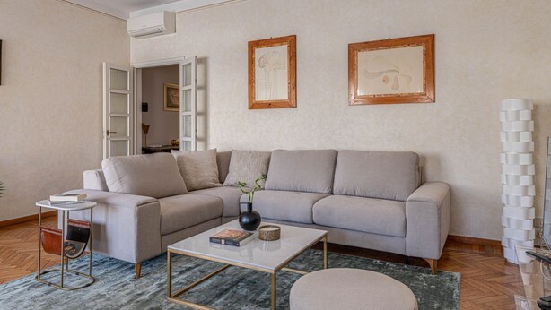 A living room with a sofa, coffee table, and a side table with a book. - Apartments Florence- Golden Tower with View (firenze)