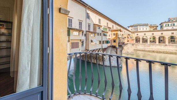 Een balkon met uitzicht op een rivier en gebouwen.