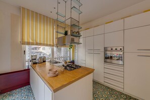A modern kitchen with a central island, stainless steel appliances, and a patterned floor. - Apartments Florence- Golden Tower with View (firenze)