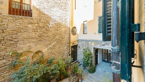 A courtyard with stone walls, potted plants, and a door leading to a building. - Apartments Florence- Golden Tower with View (firenze)