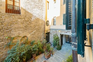 A courtyard with stone walls, potted plants, and a door leading to a building. - Apartments Florence- Golden Tower with View (firenze)