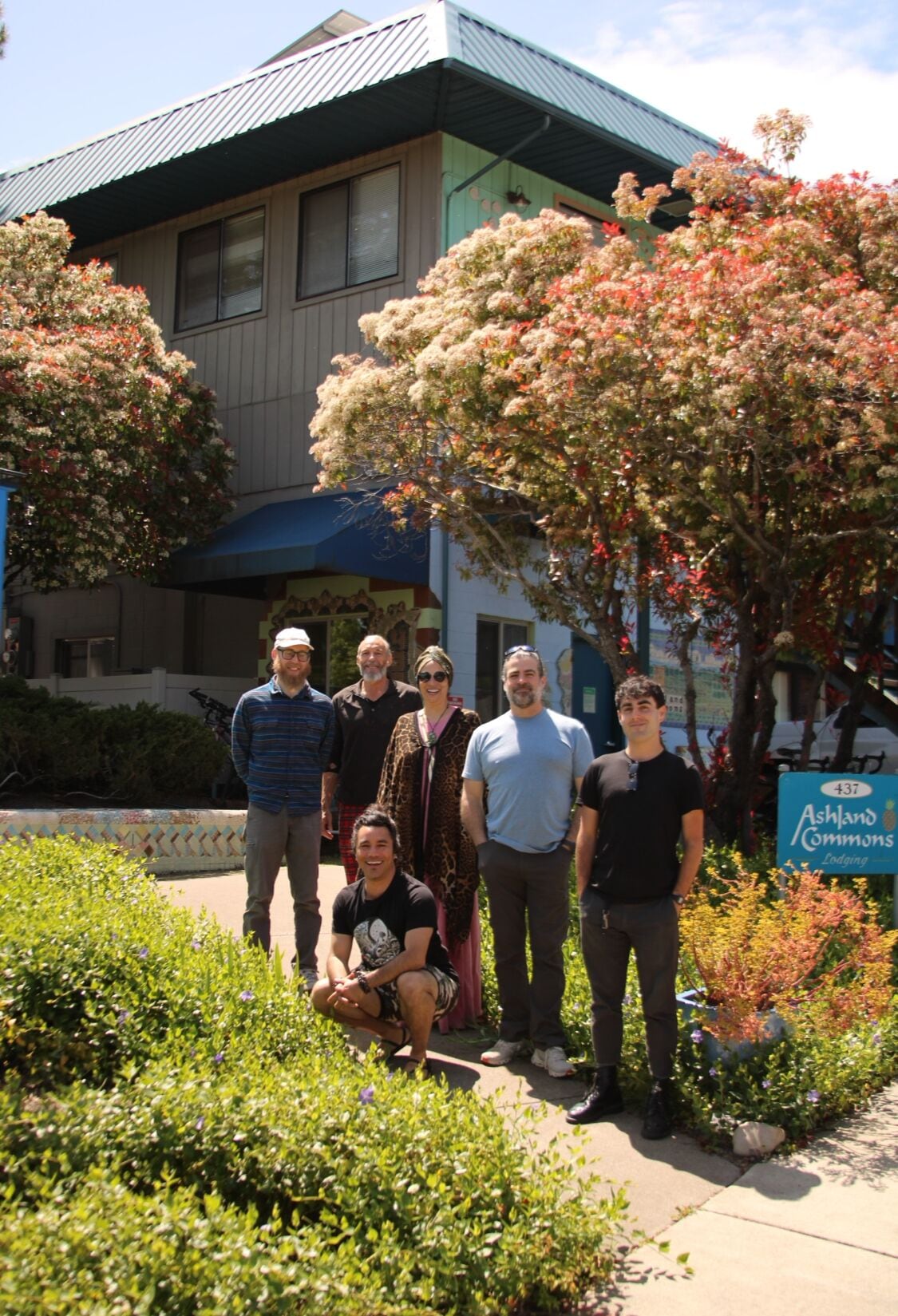 Un groupe de personnes se tient devant un bâtiment sur lequel on peut lire l’inscription : « Ashland Commons Lodging ».