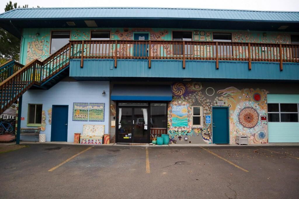 A building with a blue exterior, a balcony, and a mural on the wall.