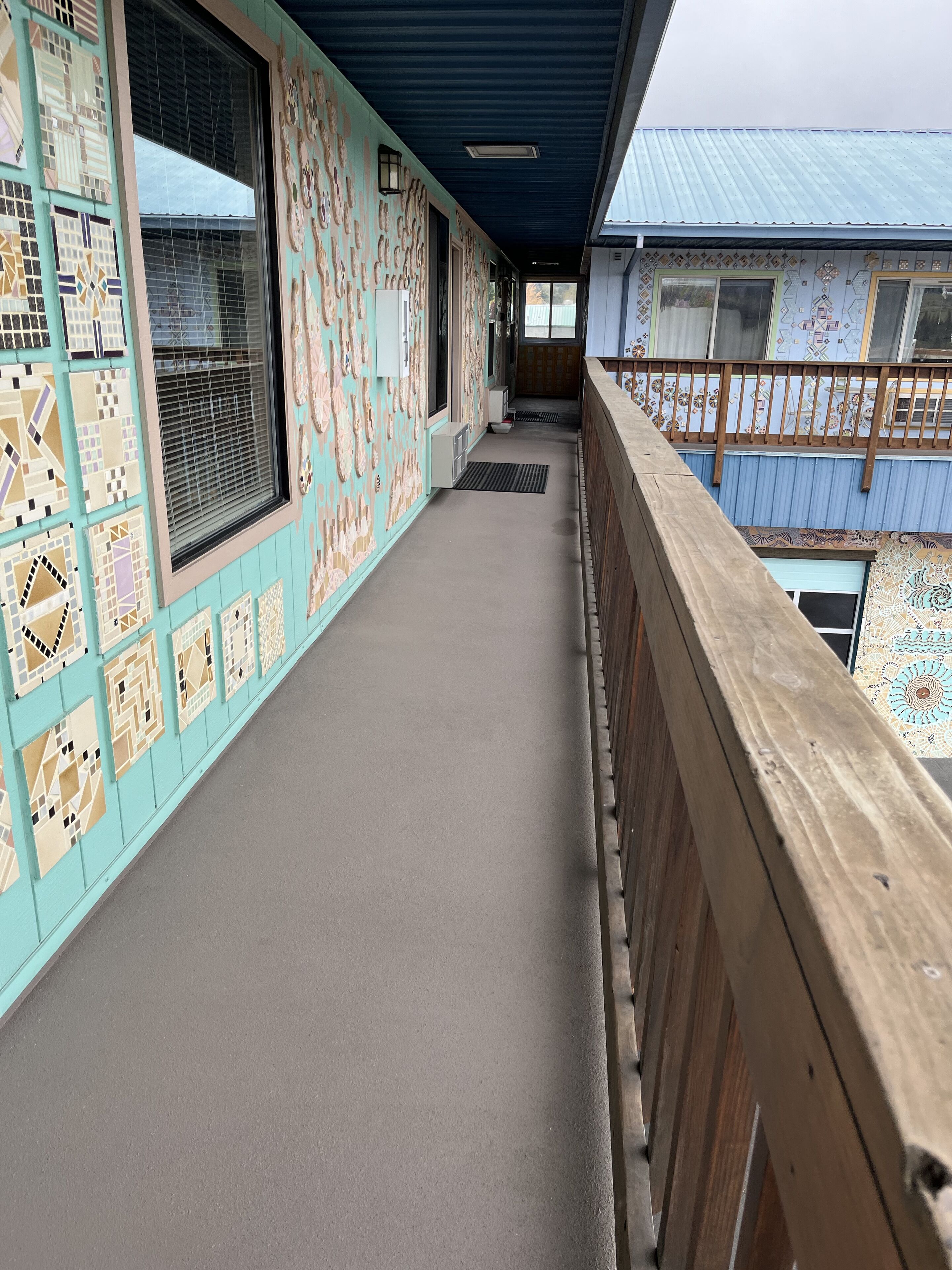 A corridor with patterned walls and a wooden railing.