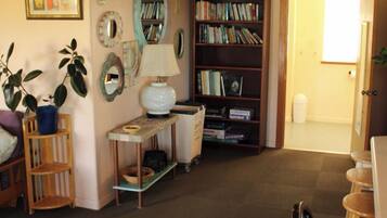 A living room with a bookshelf, a table with a lamp, and a door leading to another room.