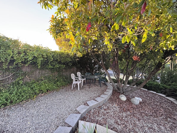 A garden area with a gravel path, a wooden fence, and a table with chairs.