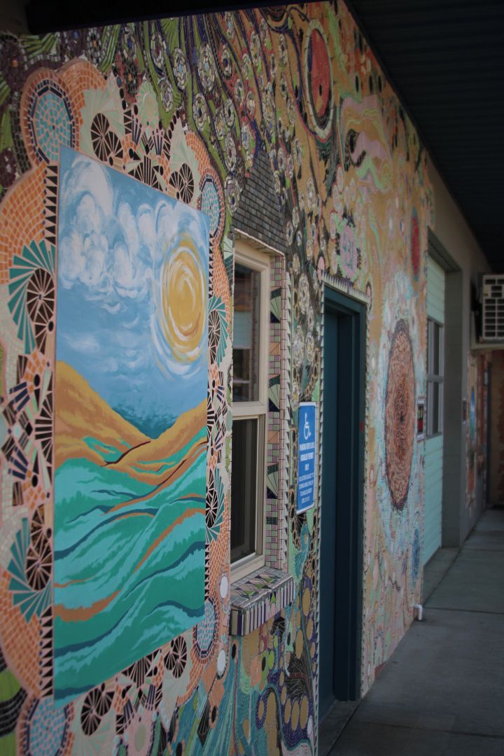 A building with a colorful mosaic wall, a window with a view, and a wheelchair accessibility sign.