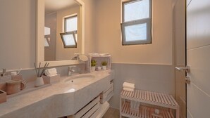 Ein modernes Badezimmer mit großem Spiegel, Waschbecken und Duschbereich.