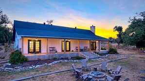 A two-story house with a covered porch, a fire pit, and outdoor seating.