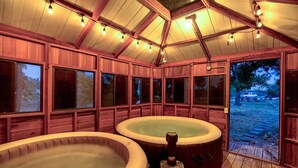 A wooden cabin with two hot tubs and a large window.