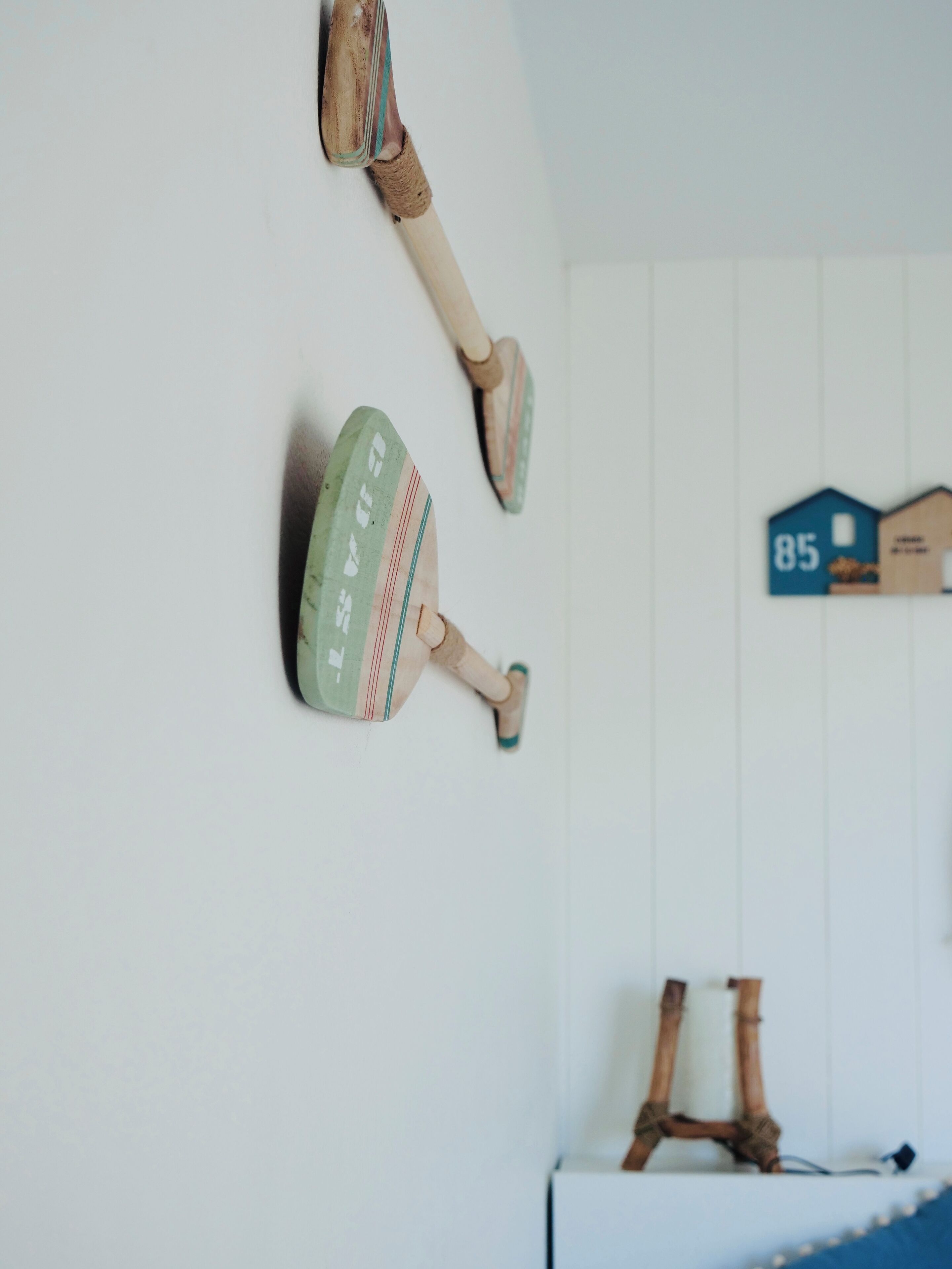 Une pièce avec un mur blanc, un plancher en bois et une petite table en bois sur laquelle se trouve une lampe.